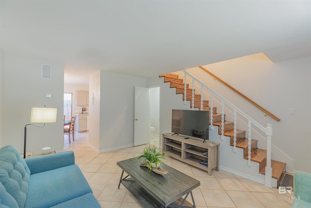 living room featuring light tile patterned flooring, visible vents, and stairs