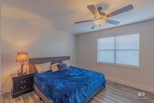 bedroom featuring light wood finished floors, a ceiling fan, and baseboards