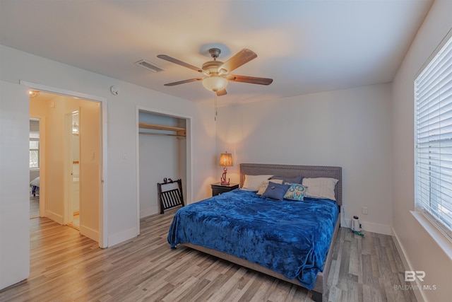 bedroom with a closet, visible vents, ceiling fan, wood finished floors, and baseboards