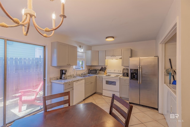 kitchen with light tile patterned floors, stainless steel appliances, gray cabinets, a chandelier, and under cabinet range hood