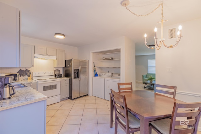 kitchen with under cabinet range hood, white electric range, visible vents, stainless steel refrigerator with ice dispenser, and washing machine and clothes dryer