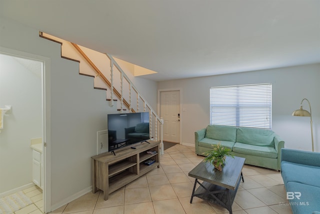 living room featuring light tile patterned floors, stairs, and baseboards