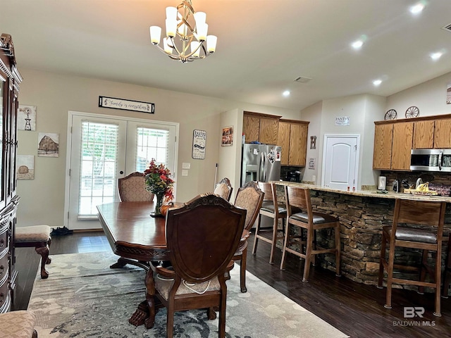 dining space with lofted ceiling, an inviting chandelier, dark wood-type flooring, and french doors