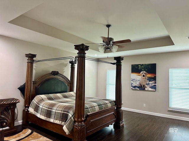 bedroom featuring a raised ceiling, dark hardwood / wood-style flooring, and ceiling fan