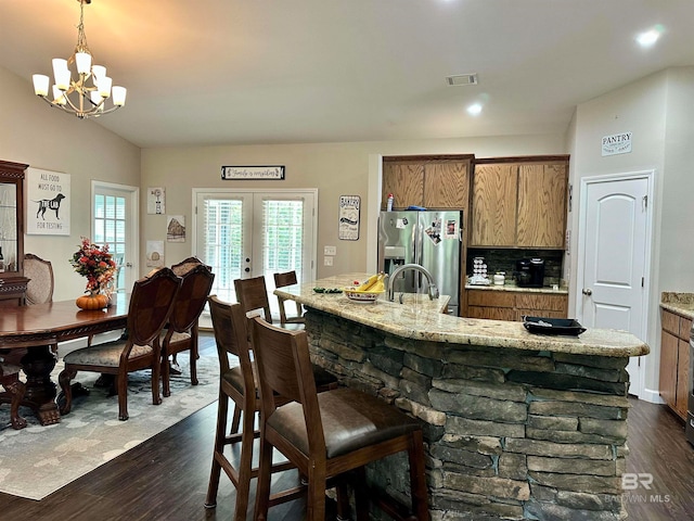 kitchen with dark wood-type flooring, lofted ceiling, decorative light fixtures, stainless steel fridge with ice dispenser, and a notable chandelier