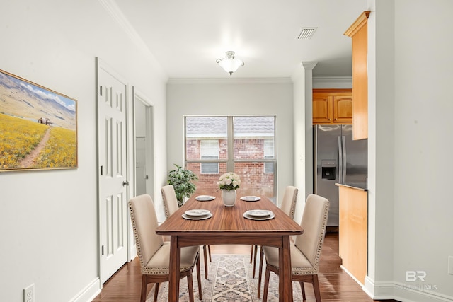 dining space featuring dark wood-style flooring, visible vents, crown molding, and baseboards