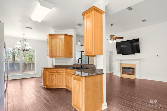 kitchen with visible vents, ornamental molding, open floor plan, a fireplace, and a sink