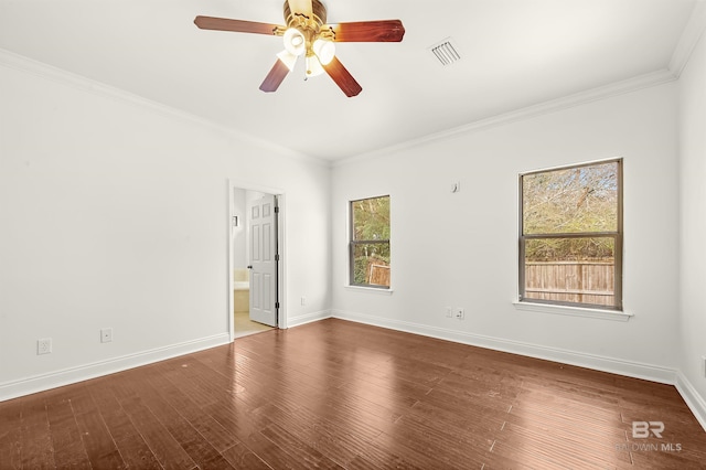 empty room with baseboards, visible vents, ornamental molding, and wood finished floors