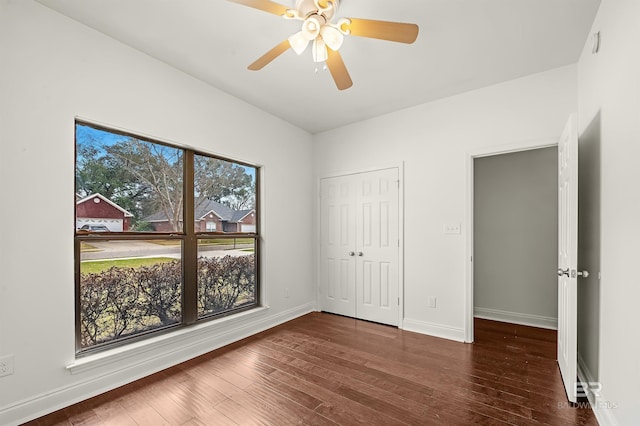 unfurnished bedroom with a closet, wood finished floors, a ceiling fan, and baseboards