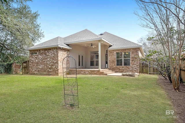 back of property with brick siding, a lawn, a shingled roof, and a fenced backyard