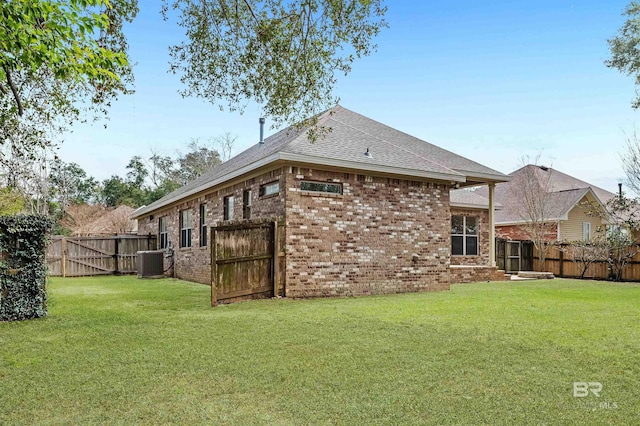 back of property featuring a fenced backyard, a lawn, and brick siding