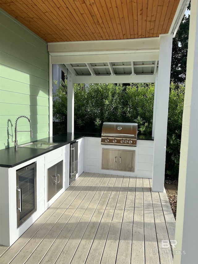 deck with wine cooler, a grill, sink, and exterior kitchen