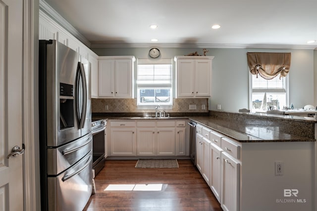 kitchen featuring dark stone countertops, appliances with stainless steel finishes, kitchen peninsula, white cabinets, and backsplash