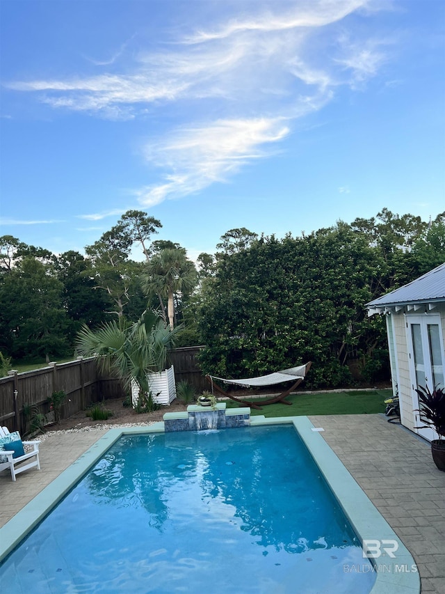 view of swimming pool with pool water feature and a patio area