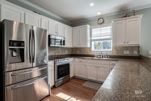 kitchen featuring hardwood / wood-style floors, sink, white cabinets, dark stone counters, and stainless steel appliances