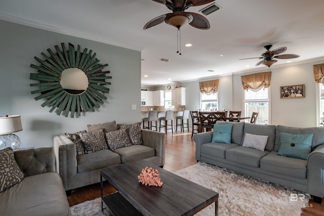 living room with ornamental molding, wood-type flooring, and ceiling fan