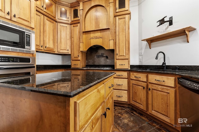 kitchen with sink, stainless steel appliances, dark stone counters, and a kitchen island