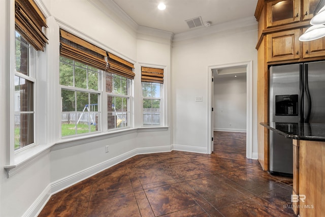 kitchen with dark stone counters, stainless steel fridge, and ornamental molding