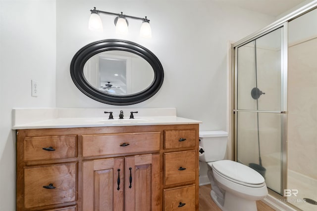 bathroom featuring a shower with shower door, toilet, and vanity