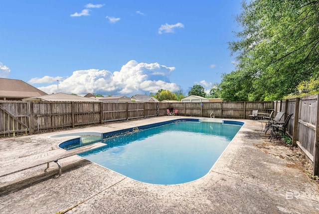 view of pool with a diving board, a patio area, and a hot tub