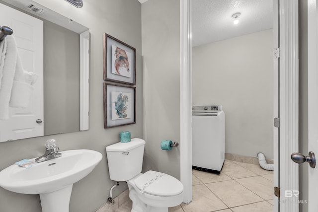 27284 Gulf Rd Unit 711, Orange Beach, AL 36561 - bathroom with washer / clothes dryer, toilet, a sink, a textured ceiling, and tile patterned floors