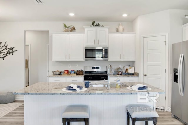 13440 Antler Hill Rd, Spanish Fort, AL 36527 - kitchen featuring stainless steel appliances, a breakfast bar area, light wood finished floors, white cabinets, and recessed lighting