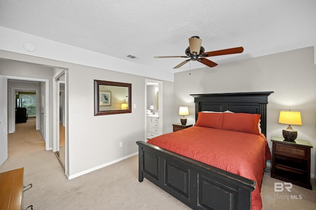 bedroom featuring ceiling fan, light colored carpet, a textured ceiling, and ensuite bathroom