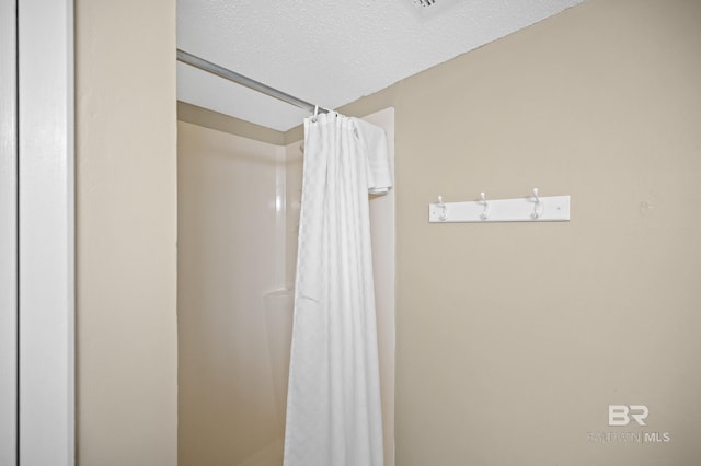 interior space featuring a textured ceiling and curtained shower