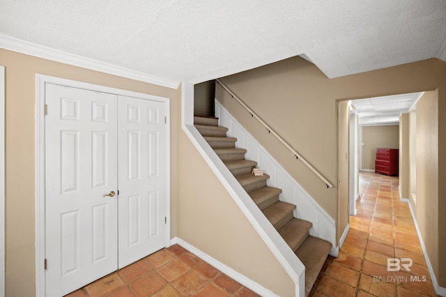 stairway with a textured ceiling and tile patterned flooring