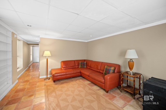 living room featuring a drop ceiling, crown molding, and tile patterned floors