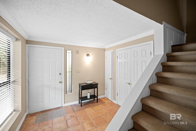 tiled foyer with a textured ceiling and ornamental molding