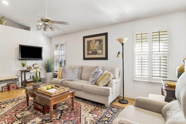 living room featuring ceiling fan, light hardwood / wood-style floors, and vaulted ceiling