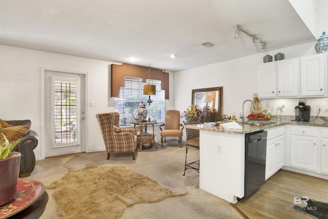 kitchen with a kitchen bar, kitchen peninsula, sink, dishwasher, and white cabinets