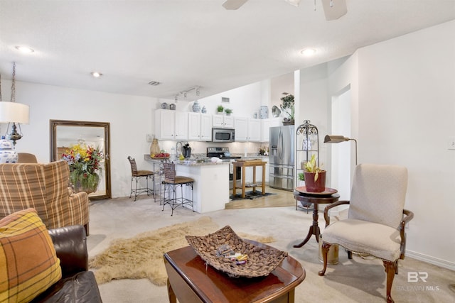 carpeted living room with rail lighting and ceiling fan