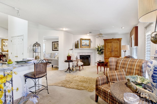 living room featuring light carpet, a tile fireplace, and ceiling fan