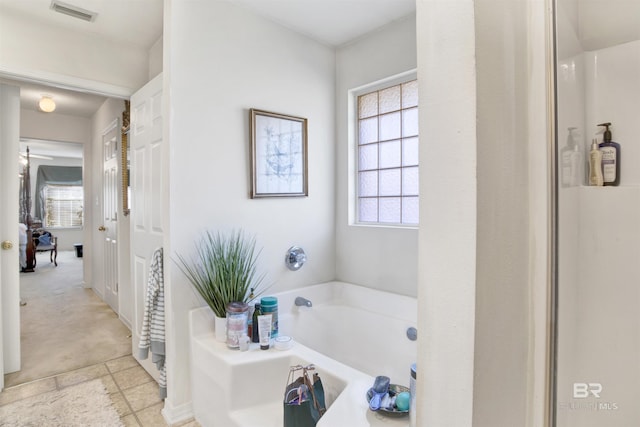 bathroom featuring a bathing tub, plenty of natural light, and tile patterned flooring