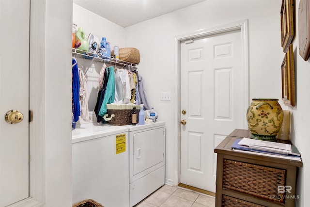 washroom with washer and clothes dryer, light tile patterned flooring, and a textured ceiling