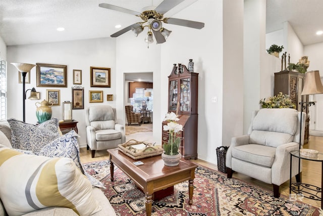 living room featuring a textured ceiling, light hardwood / wood-style floors, ceiling fan, and lofted ceiling