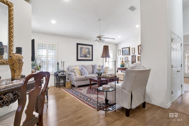 living room with wood-type flooring, ceiling fan, and lofted ceiling