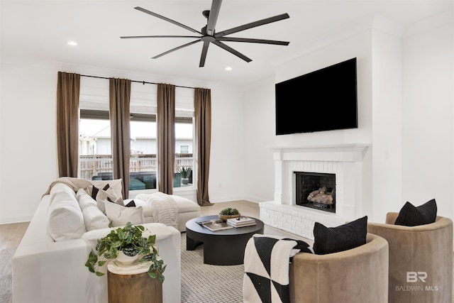 living room with ornamental molding, ceiling fan, and a fireplace