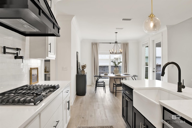 kitchen with white cabinetry, premium range hood, pendant lighting, and dishwashing machine