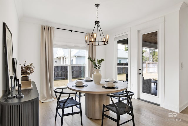 dining space featuring plenty of natural light, ornamental molding, a chandelier, and light wood-type flooring