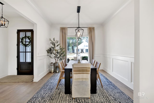 dining room featuring crown molding, wood-type flooring, and an inviting chandelier