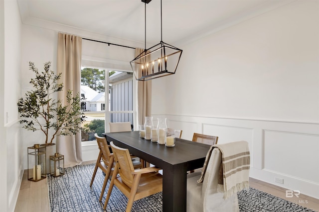 dining space with crown molding, an inviting chandelier, and light hardwood / wood-style floors