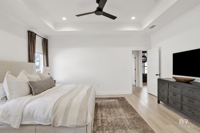 bedroom featuring ceiling fan, a tray ceiling, and light hardwood / wood-style floors