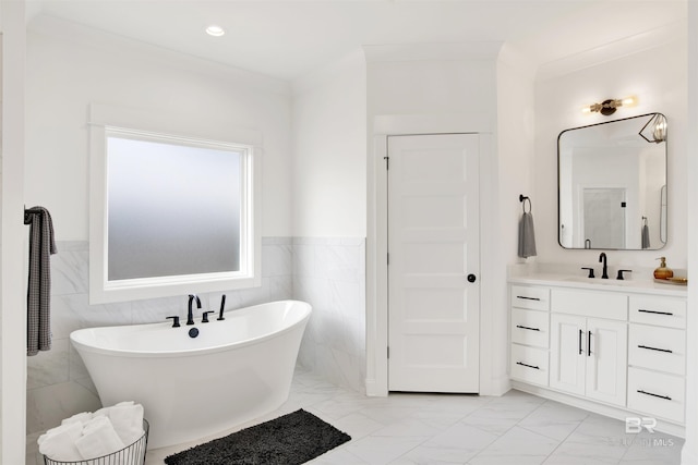 bathroom with ornamental molding, vanity, a bathing tub, and tile walls