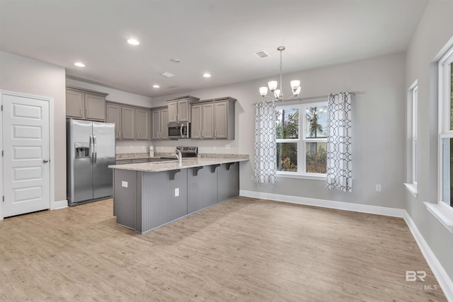 kitchen with sink, a breakfast bar area, hanging light fixtures, kitchen peninsula, and stainless steel appliances