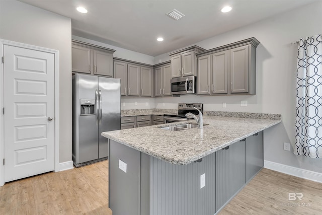 kitchen featuring appliances with stainless steel finishes, sink, gray cabinetry, kitchen peninsula, and light hardwood / wood-style flooring