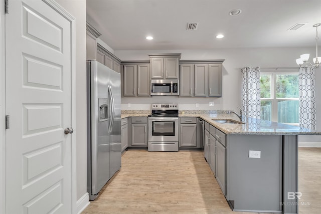 kitchen featuring sink, light stone counters, hanging light fixtures, gray cabinets, and stainless steel appliances