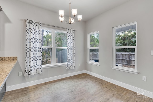 unfurnished dining area featuring an inviting chandelier and hardwood / wood-style floors